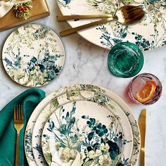 the table is set with plates, silverware and green napkins