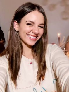 a woman is smiling and holding up her cell phone to take a selfie with candles in the background