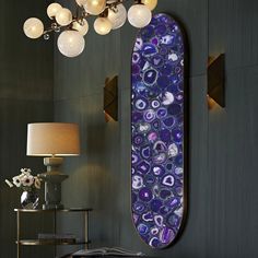 a purple and blue wall hanging next to a table with a lamp on top of it