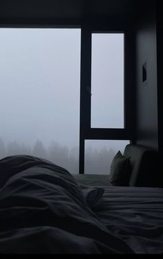 a bed sitting next to a window in a room with foggy walls and floor