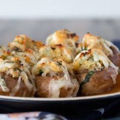 stuffed mushrooms covered in cheese and herbs on a plate