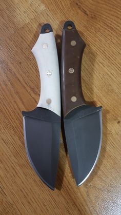 two knives sitting side by side on top of a wooden table with holes in them