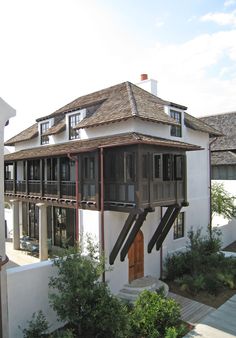 a large white house with a brown roof and wooden balconies on the second floor