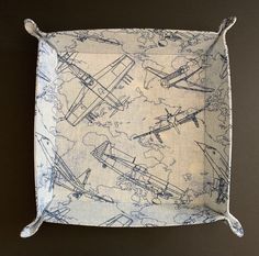 a blue and white pillow with airplanes on it's side, sitting on a black surface