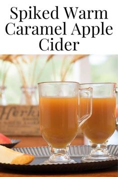 two glasses of spiced warm caramel apple cider on a tray with apples in the background