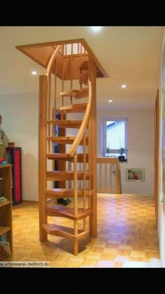 a man standing next to a spiral staircase in a room with bookshelves on the floor