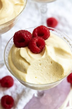 two desserts with raspberries and cream in glasses on a white tablecloth