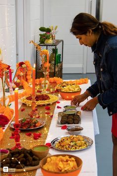 a woman standing in front of a long table filled with plates and bowls full of food