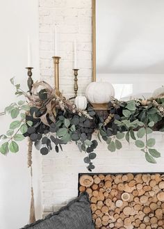 a fireplace mantel with candles and greenery on it