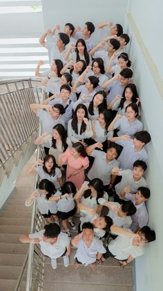 a large group of people standing on top of a stair case next to each other