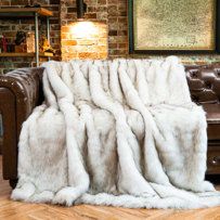 a couch with a blanket on top of it in front of a brick wall and wooden floor