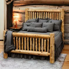 a wooden bed frame with grey linens and pillows in a rustic cabin style bedroom