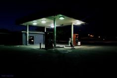 an empty gas station at night with the lights on