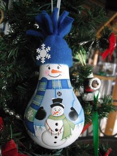 an ornament hanging from a christmas tree with snowman and penguin on it