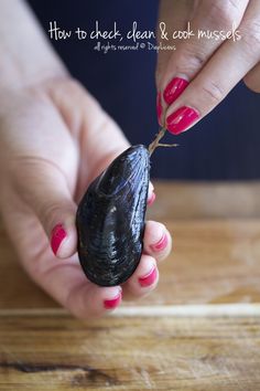 a woman holding a tiny black object in her hand with pink nail polish on it