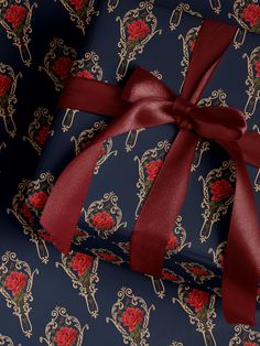 a blue gift box with a red ribbon tied around it's neck and an ornate pattern on the wrapping paper