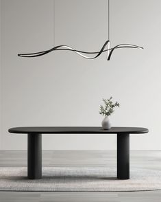 a table with a vase on it and some lights hanging from the ceiling over it