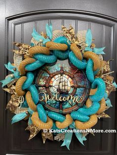 a blue and gold wreath with the word welcome on it's front door, decorated with seashells