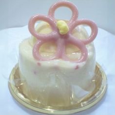 a cake with pink icing and a flower decoration on top is sitting on a gold plate