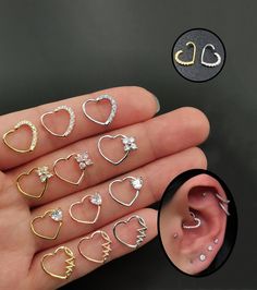 a person holding their ear with different types of piercings on it, including hearts and stars