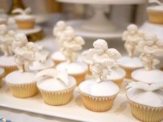 cupcakes with white frosting and figurines are on a tray next to each other