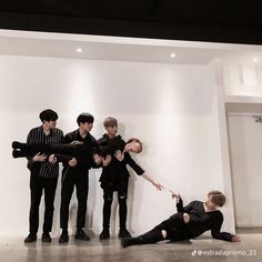 the group of young men are posing in front of a white wall with their arms around each other