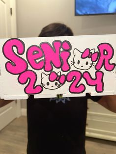 a person holding up a sign with hello kitty on it's side in front of their face