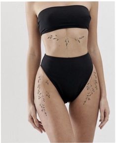 a woman in a black bikinisuit with tattoos on her stomach and the bottom part of her body