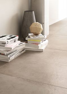 a stack of books sitting on top of a floor next to a vase