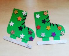 two pieces of green paper with flowers and leaves on them, one cut out to look like a shoe