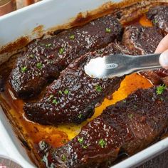 a person is spooning some food out of a casserole dish with meat