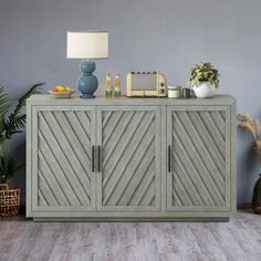 a sideboard with drawers in the middle of a room next to potted plants