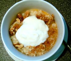 a white bowl filled with oatmeal and nuts on top of a table