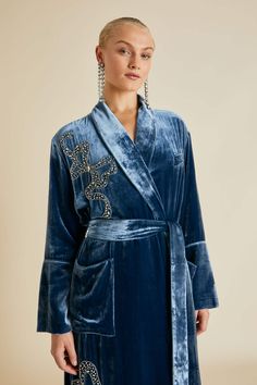 As sophisticated as she is seductive, our Capability robe is crafted from opulent steel blue silk velvet. She is adorned with shimmering bows: a homage to artist Mary Blair, whose illustrations were as playful as they were pioneering. Crafted by artisans in India using the age-old Aari technique, these exquisite bows took thirty-five hours to embellish by hand. Match with our Fifi Grace Pyjamas and Contessa Grace slippers and treasure forever. Product Details Blue bow embellishment Tonal piped silk trims Fully lined Velvet sash with belt loops Internal stay tie Product code BL0012 Materials and Care Olivia von Halle products are made using the finest natural materials This item is made from 82% Rayon, 18% Silk We recommend dry cleaning only due to the delicate nature of this piece Do not i Camp Christmas, Mary Blair, Luxury Sleepwear, Olivia Von Halle, Clothes Making, Velvet Suit, Embroidered Monogram, Gold Silk, Silk Pajamas