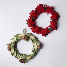 two christmas wreaths with pine cones and red felt flowers on white background, top view