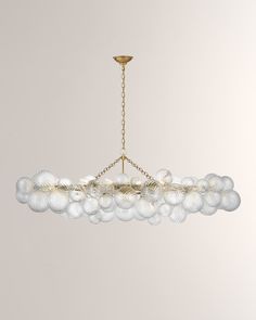 a chandelier hanging from a gold chain with white glass balls in the center