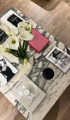 a marble coffee table topped with books and flowers