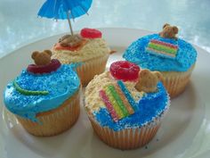 four cupcakes with blue frosting and teddy bears on top are sitting on a plate