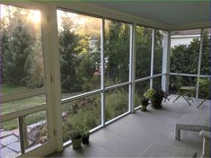 the sun shines through two large windows onto a deck with chairs and potted plants