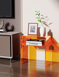 an orange table with some books and a vase on it in front of a wall