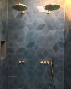 a bathroom with blue tiled walls and gold shower faucets on the wall, along with brass fixtures