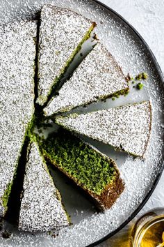 a cake that has been cut into slices on a platter with two glasses next to it