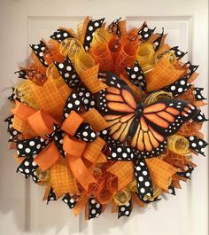 an orange and black mesh wreath with a butterfly on the front door, decorated with polka dots