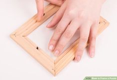 a person's hand is touching the bottom of a wooden frame with their fingers