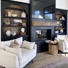 a white couch sitting in front of a black book shelf filled with vases and other items