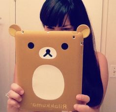 a woman holding up a brown ipad case with a bear on it's face