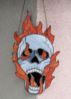 a skull hanging from a chain with flames coming out of it's mouth and eyes