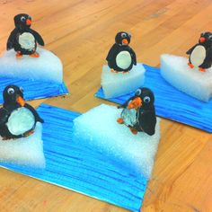 four penguins sitting on top of an iceberg in the middle of a wooden floor