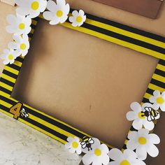 a yellow and black striped frame with flowers on the bottom is sitting on a table