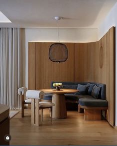 a living room filled with furniture next to a wooden table and white curtains on the windowsill